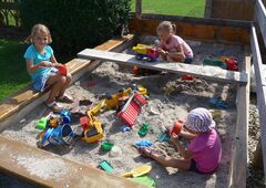 Kinder spielen im Sandkasten auf dem Bauernhof im Allgäu
